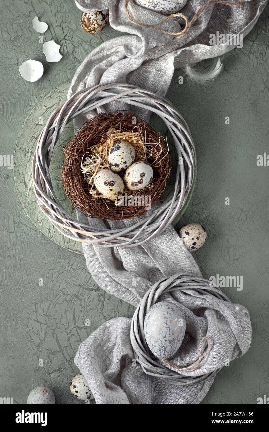 Easter flat lay on dark background with quail eggs in the nest, linen ...
