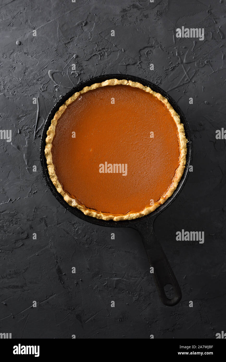 Homemade open pumpkin pie in cast iron pan on black background top view copy space overhead view Stock Photo
