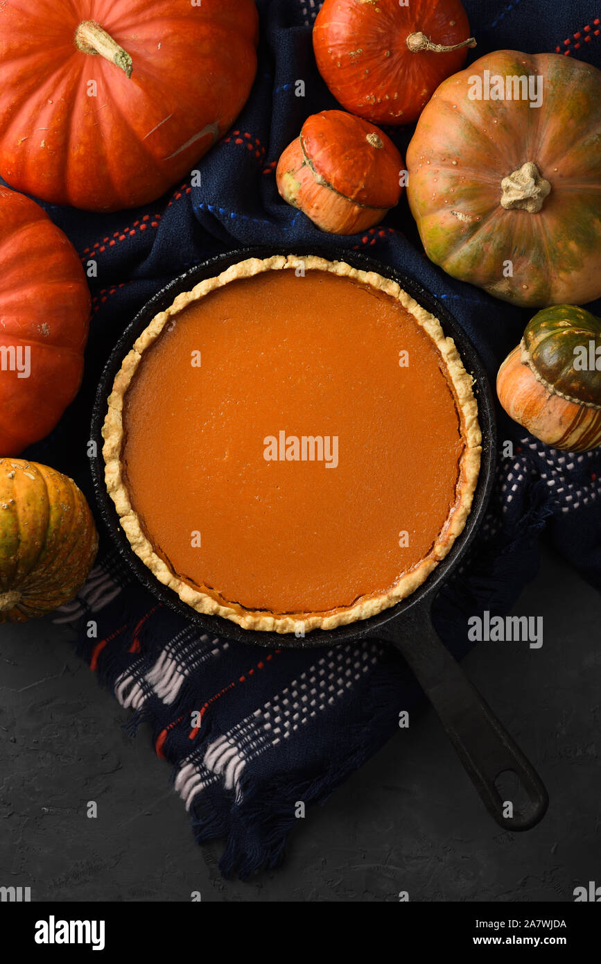 Hygge still life flat lay. Traditional pumpkin pie and winter squashes on black background copy space Stock Photo