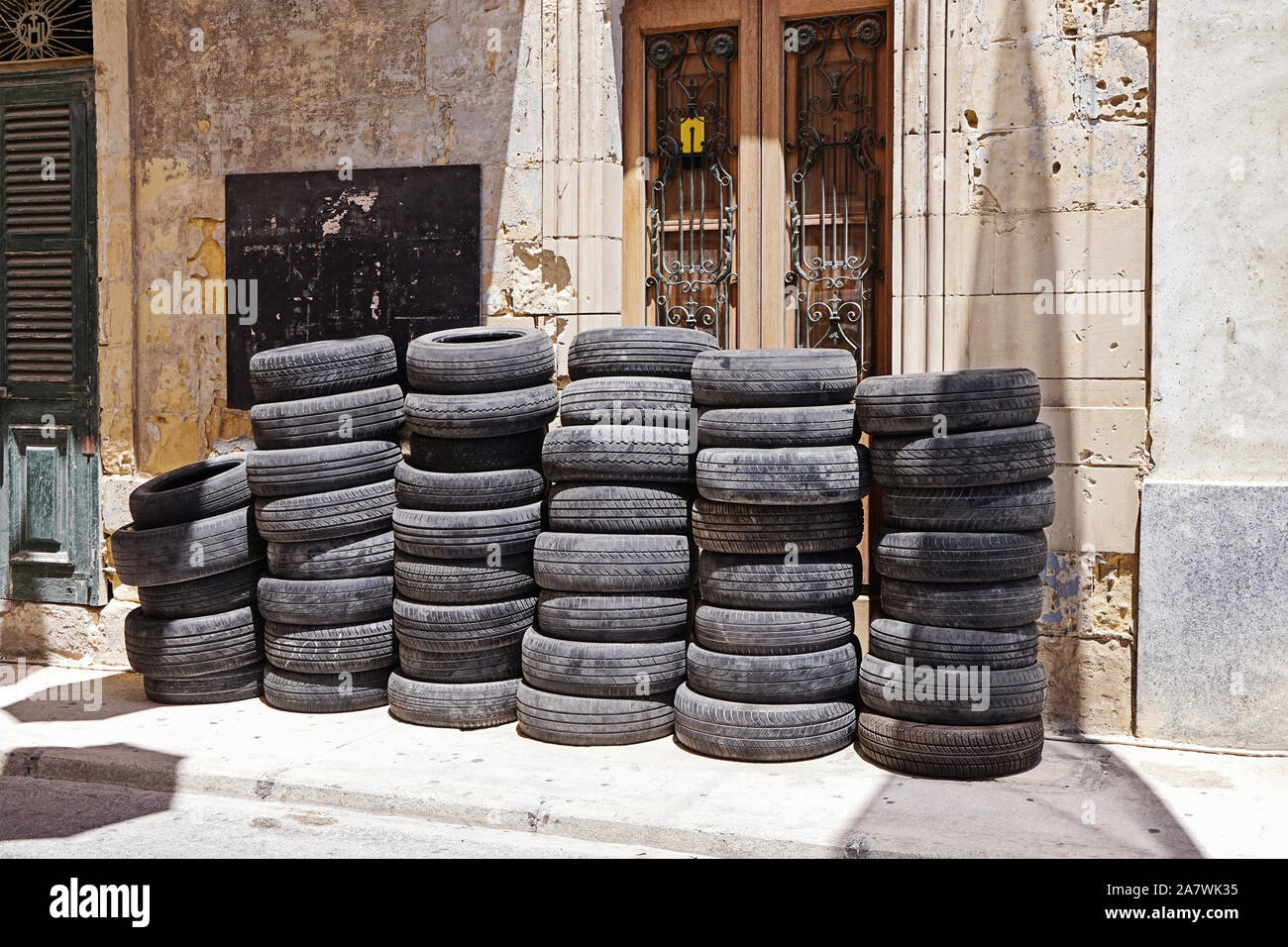 Pile of used car rubber tires near auto garage on street. Tyre fitting