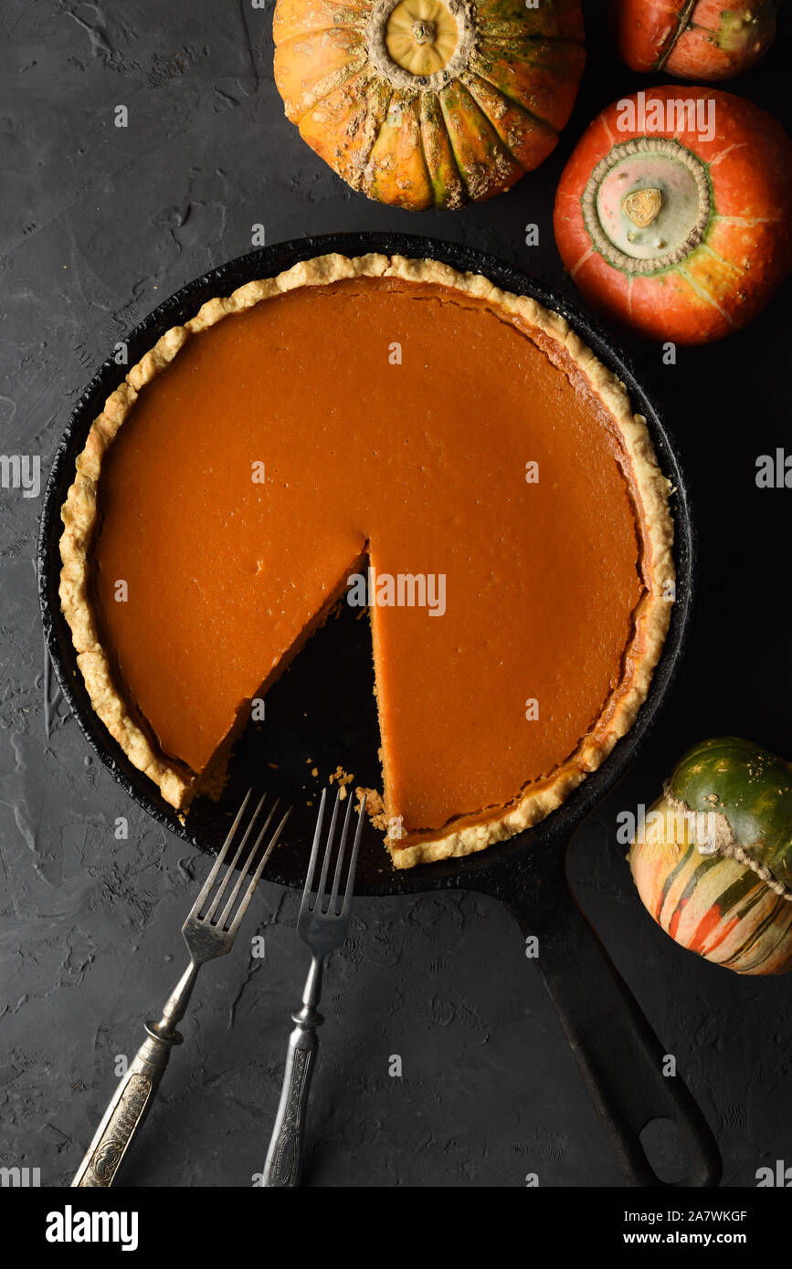 Homemade pumpkin pie in cast iron pan on black background top view copy space. Hygge or home baking concept above view Stock Photo