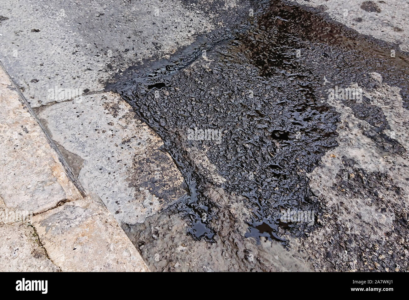Wet black spot by engine oil on surface of road. Environmental