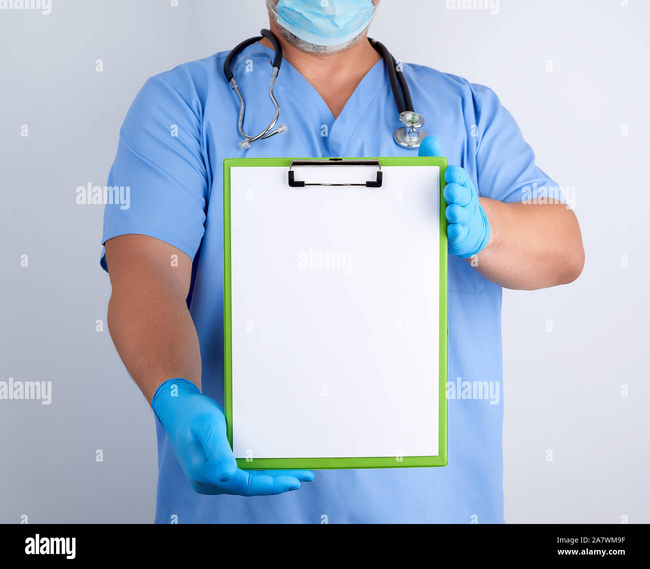 doctor in blue uniform and latex gloves holds a green holder for sheets ...