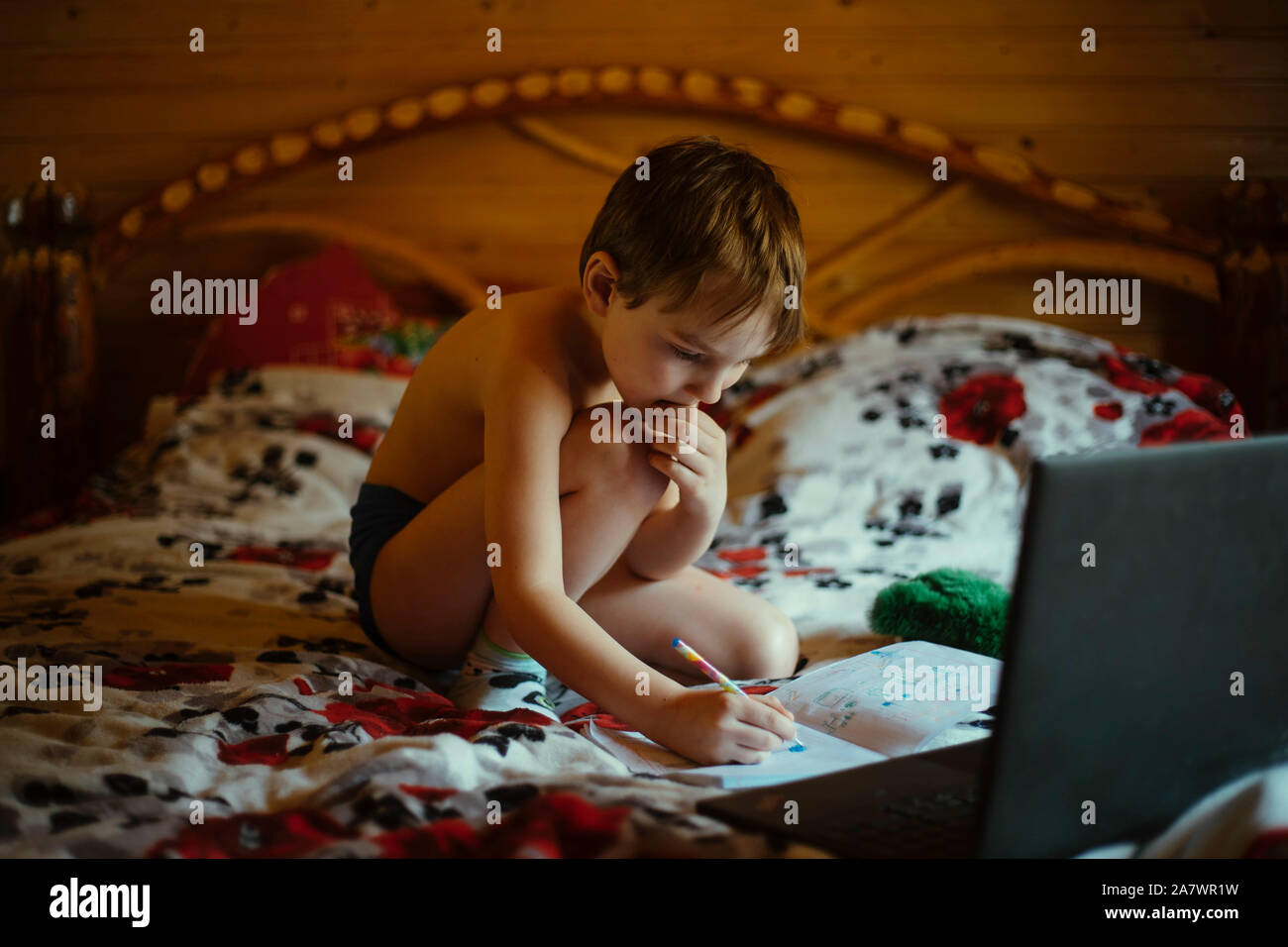 the child does homework while sitting on the bed Stock Photo