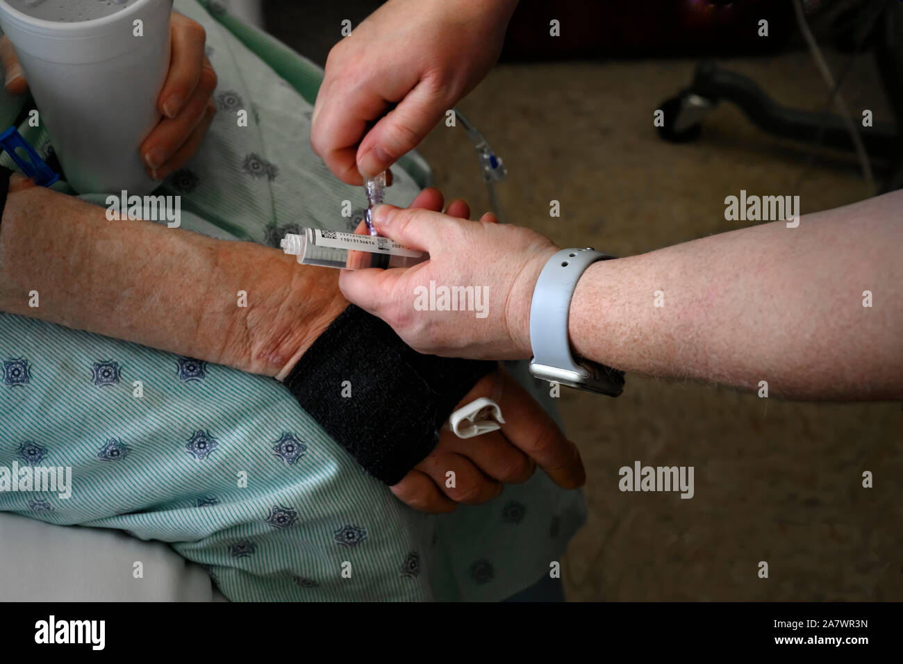 close up of a nurse inserting a saline needle syringe into the arm of a