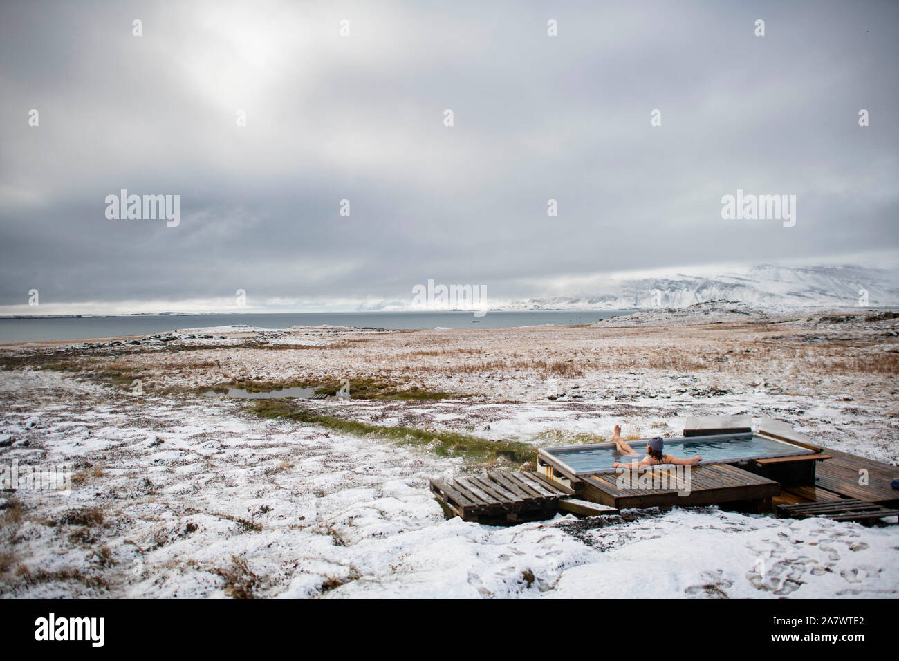 A man enjoying a natural hot springs after a fresh snow, Iceland. Stock Photo