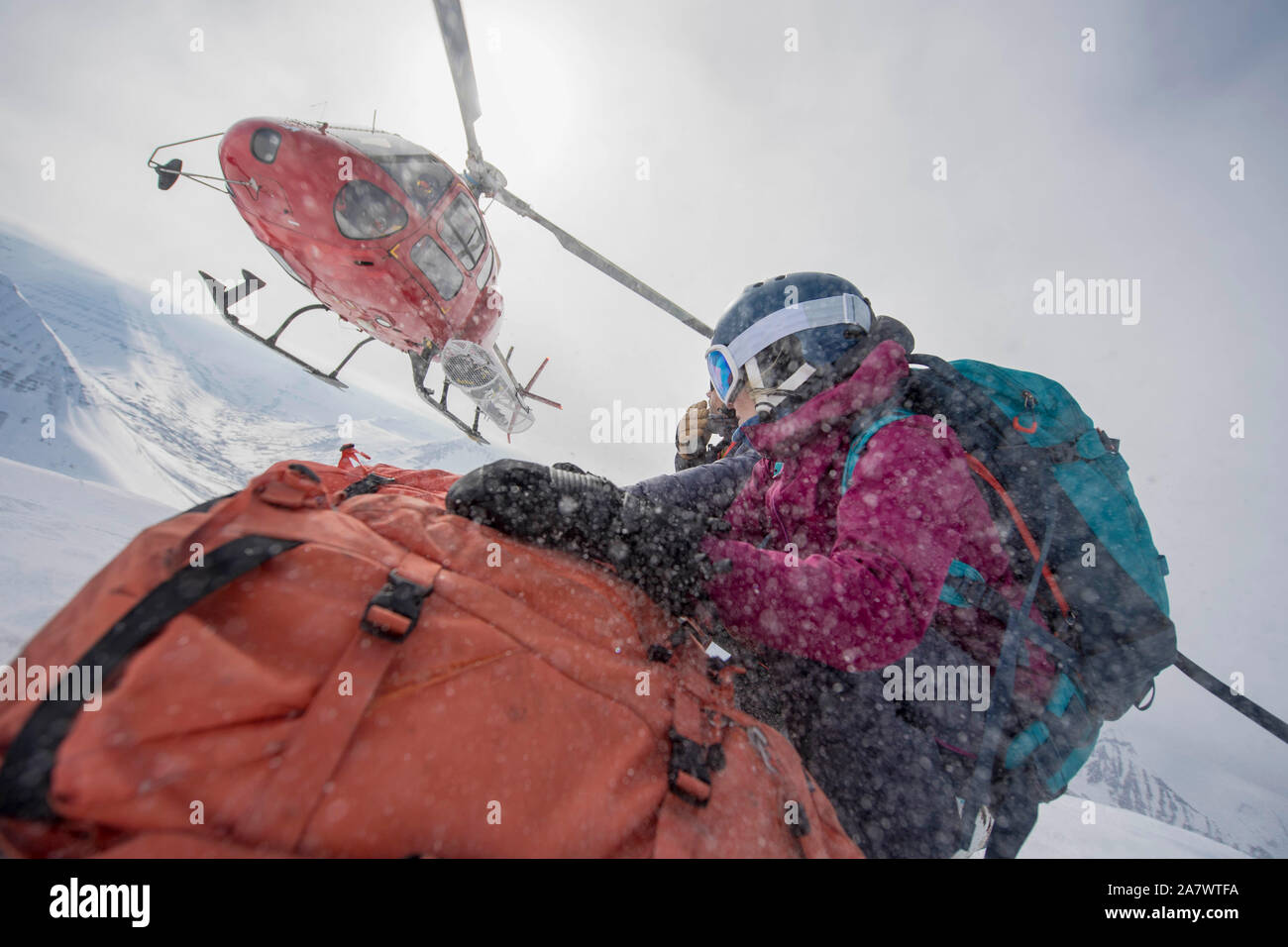 A female skier being dropped off by a helicopter. Stock Photo