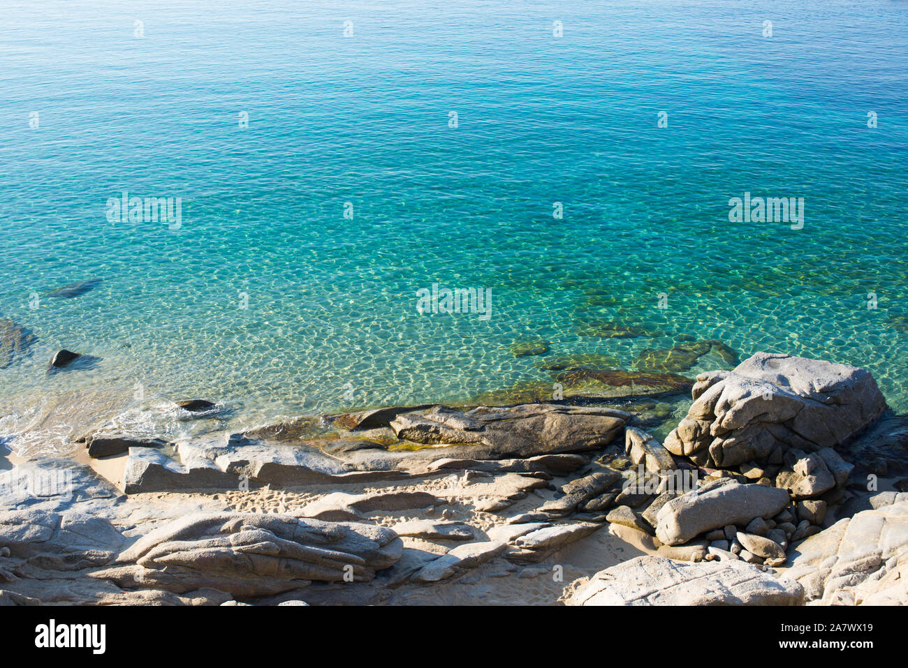 Rocky beach shore with pristine clear blue green sea water. Stock Photo