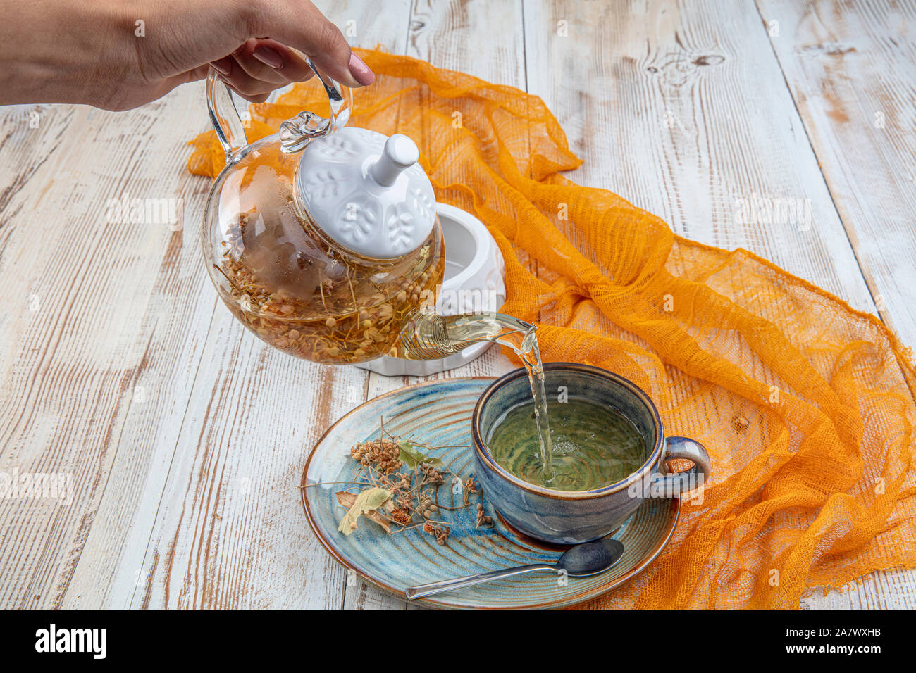 transparent glass teapot and cup with linden tea. Medicinal plant ...