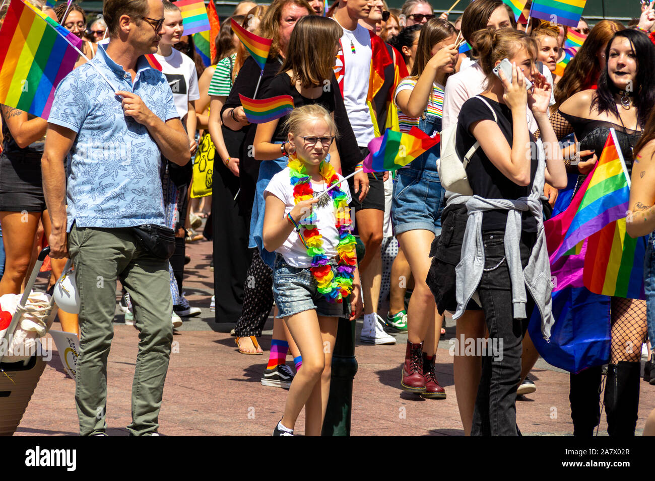 Malmö, Sweden - July 20 2019: A young girl in glasses with a sceptical look waves her rainbow colored pride flag while attending the 2019 pride parade Stock Photo