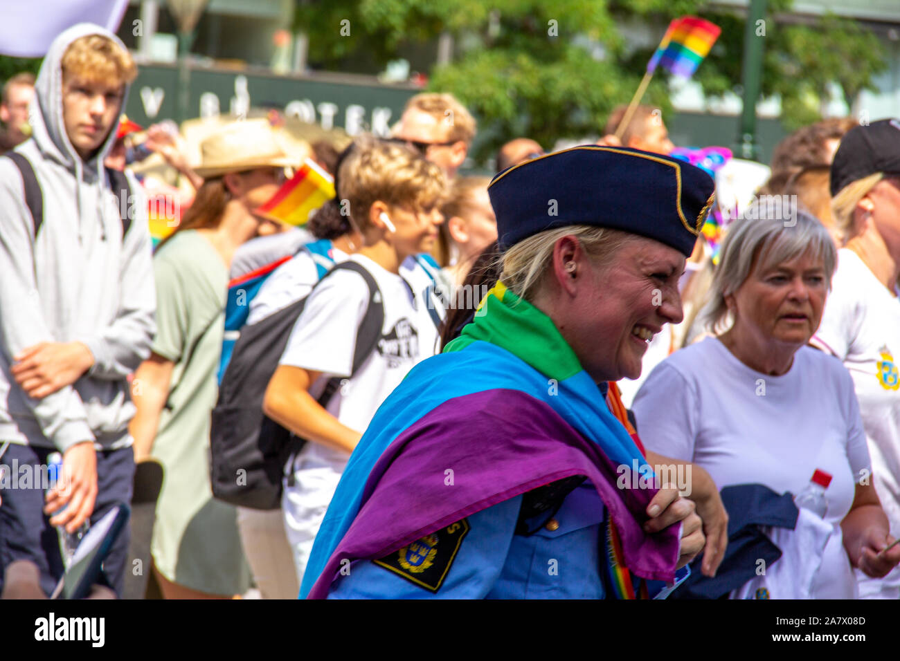 A Swedish police woman with rainbow flag around her shoulders is laughing with happiness as she participates in the annual gay pride parade in Malmö Stock Photo