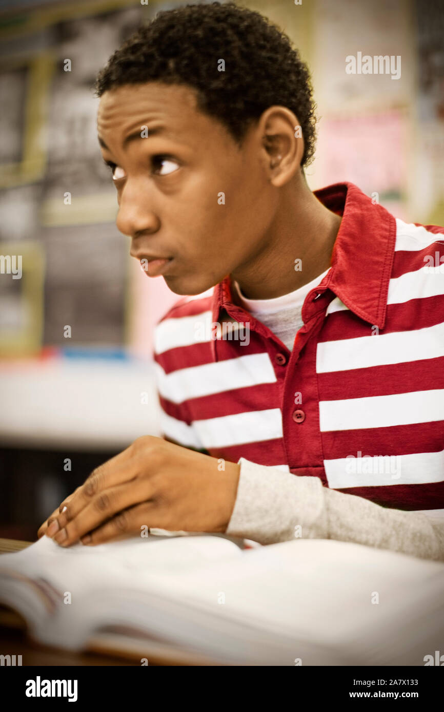 Teenage boy reading in a classroom Stock Photo - Alamy