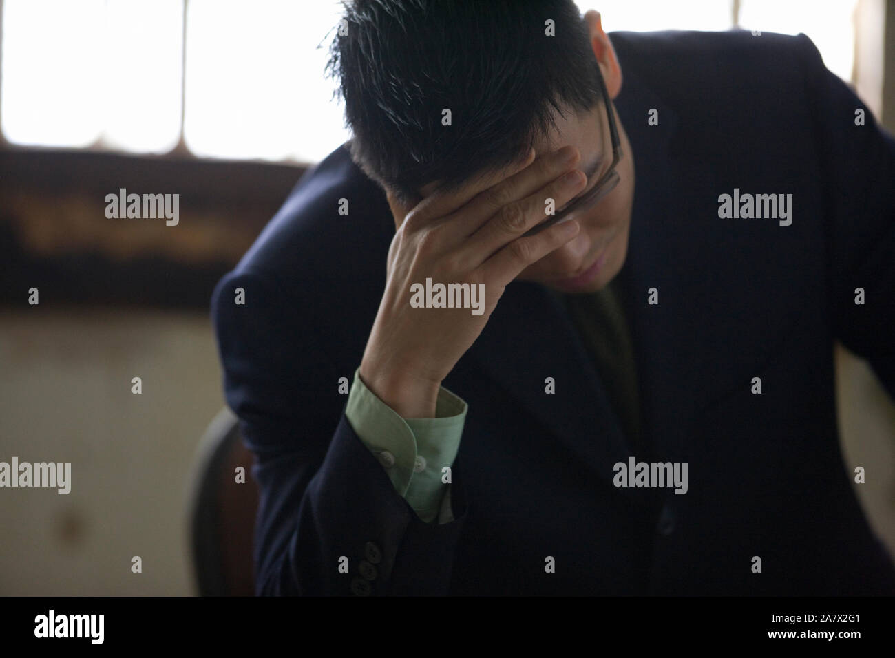 Despairing young businessman sitting with his hand on his forehead. Stock Photo