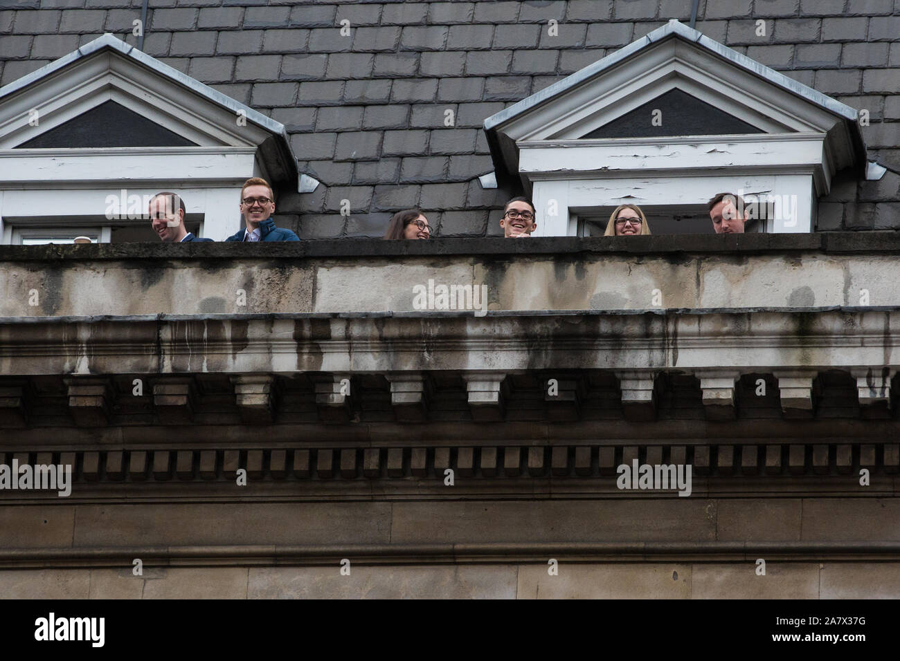 London, UK. 14 October, 2019. Office workers watch from a rooftop high above Parliament Street shortly before the arrival of the Queen en route to the Stock Photo