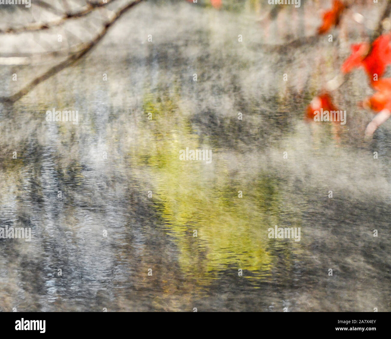 Fall leaves reflected in water - fall colors - fall trees reflecting - impressionism - impressionist photography - steam fog - misty water Stock Photo
