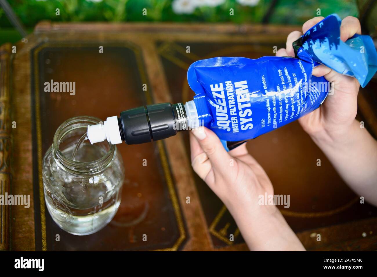 Young man using Sawyer Squeeze Water Filtration System to purify water