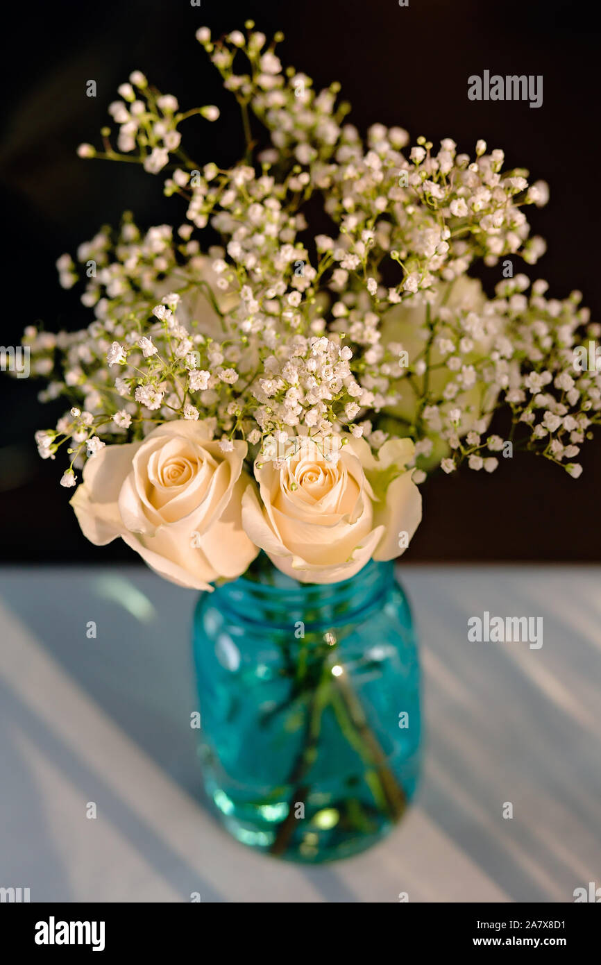 Bouquet Of White Roses And Babies Breath Flowers In A Blue Glass