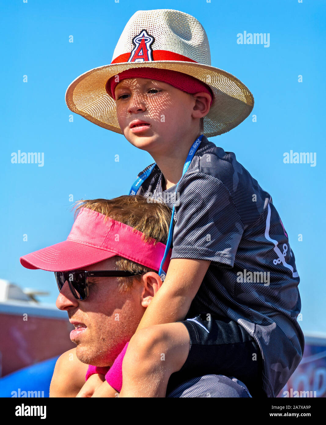 Anaheim, CA / USA - Nov 3, 2019: Son wearing hat sits on his dad's shoulders against a blue sky at the 2019 JDRF One Walk fundraiser. Type 1 diabetes. Stock Photo