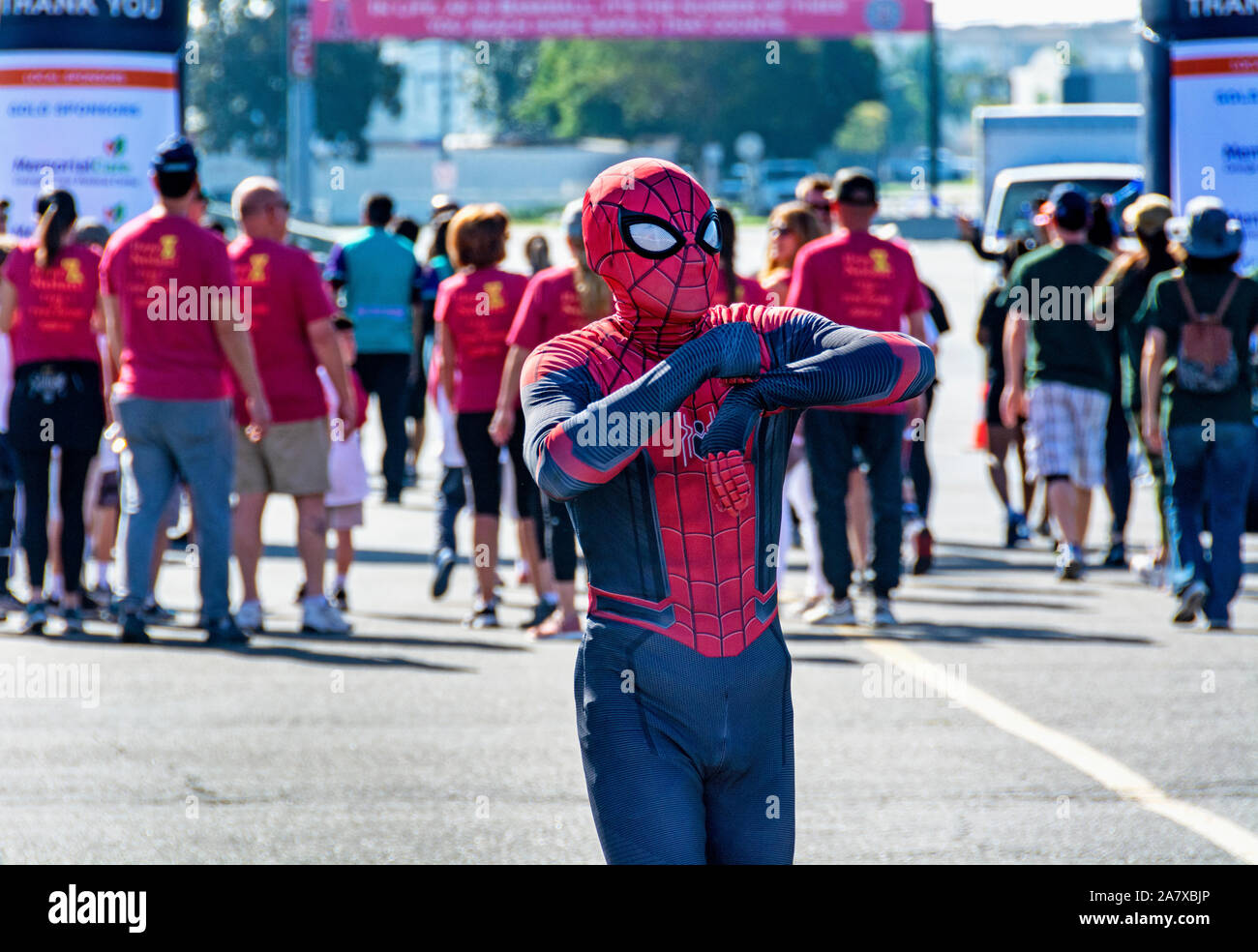 Closeup of man dressed in Spiderman costume dances to amuse the crowd as they cross the finish line to raise money for Type 1 diabetes. JDRF One Walk. Stock Photo