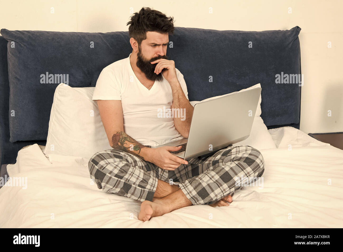 Just woke up and already at work. Man surfing internet or work online. Hipster bearded guy pajamas freelance worker. Remote work concept. Social networks internet addiction. Online shopping. Stock Photo