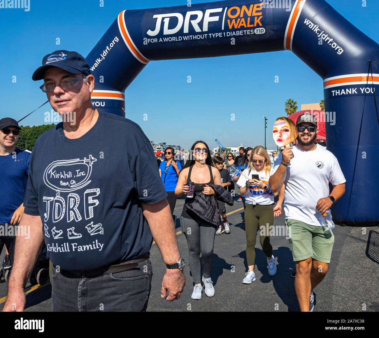 Anaheim, CA / USA - Nov 3, 2019: A group of people of mixed ages and ethnicity cross the finish line at the 2019 JDRF One Walk at Angel Stadium. Stock Photo