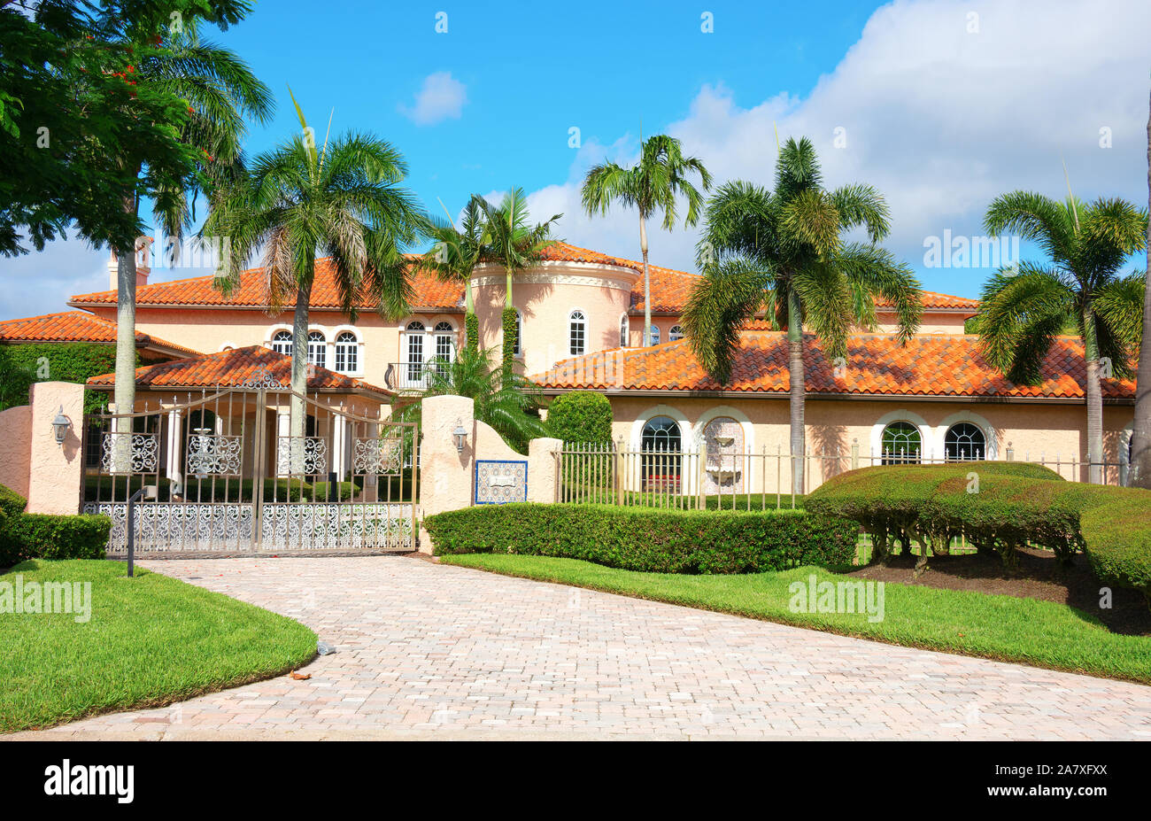 Beautiful Spanish style luxury mansion residential home with a privacy gate and palm trees on a blue sky sunny morning. Stock Photo