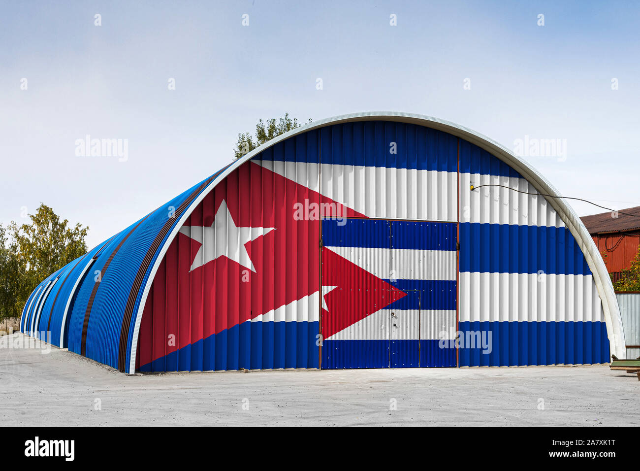 Close-up of the national flag of Cuba  painted on the metal wall of a large warehouse the closed territory against blue sky. The concept of storage of Stock Photo