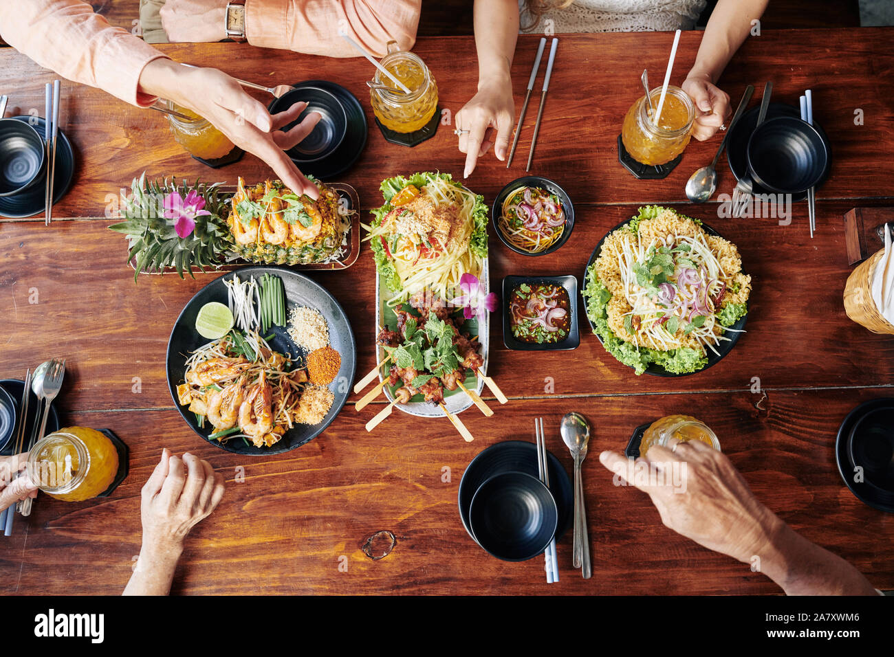 Group of people having dinner with various traditional Asian dishes and