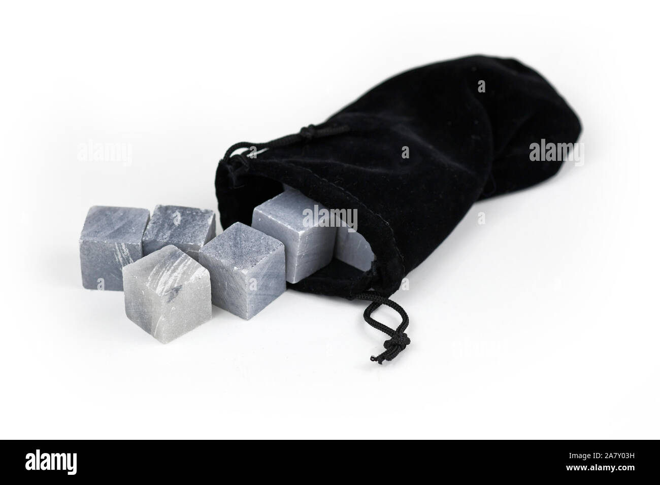 Gray Whisky chilling stones, a substitute for ice cubes to prevent  diluting a drink, coming out of black pouch isolated on white background Stock Photo