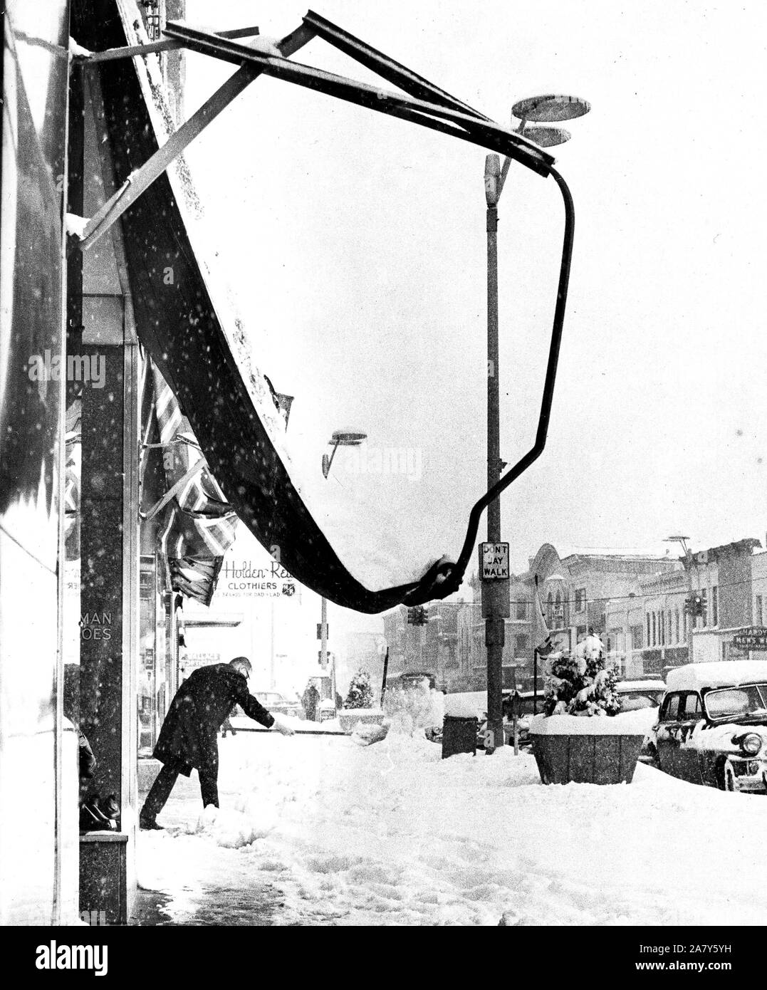 Man Shoveling Snow on City Sidewalk; Collapsed Awning in Foreground November 1966 Stock Photo