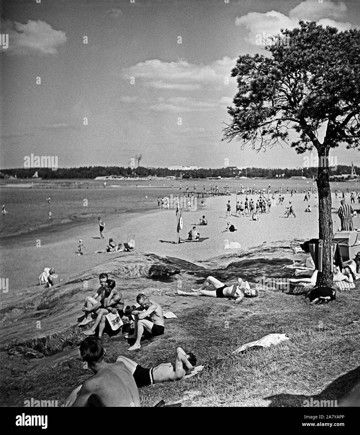Helsinki, Hietaniemi beach, June 1948. People sunbathing. In the horizon Taivalluoto and Rajasaari. Helsinki. Hietaniemen uimaranta, näkymä kohti Taivalluotoa ja Rajasaarta. Auringonottajia uimarannalla. Stock Photo