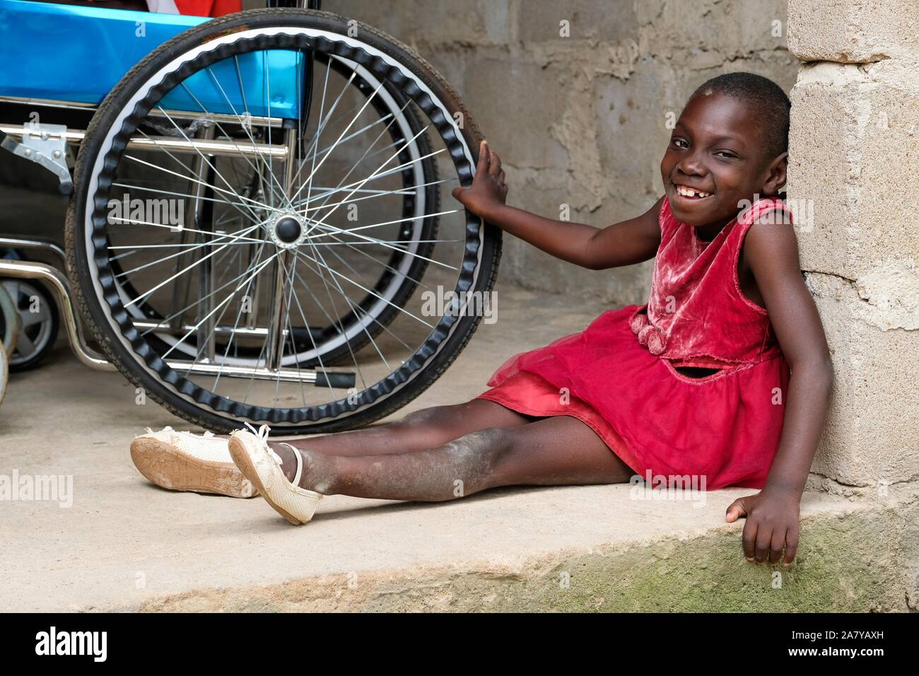 Disabled girl sitting next to her wheelchair at the 'Nazareth Home for God's Children', home for children with mental and physical disabilities of  in Sang / Ghana Stock Photo