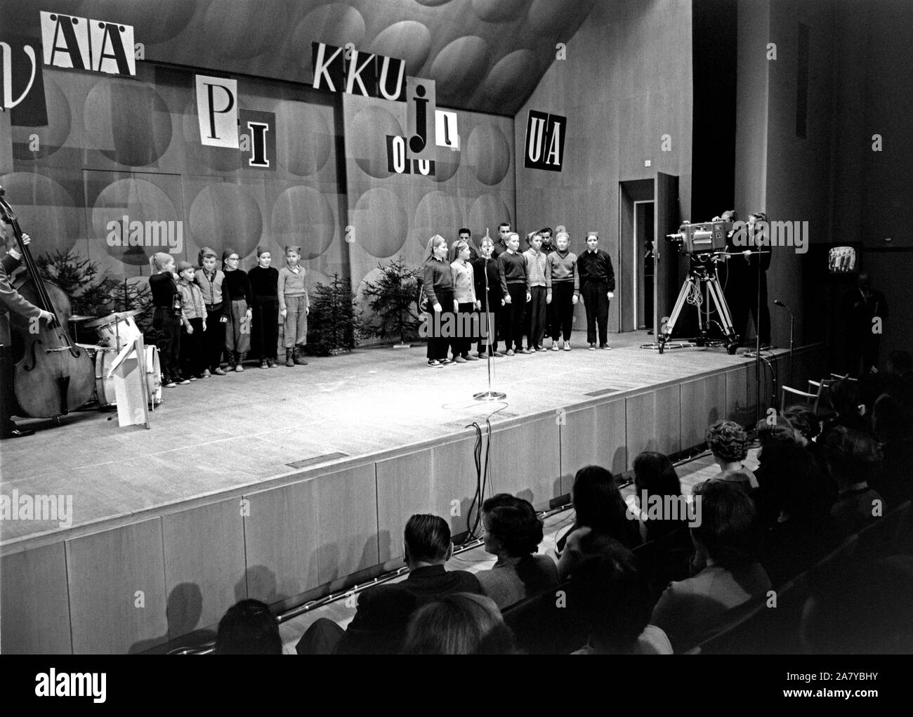 Yleisradion televisiotoiminnan ensimmäinen julkinen televisioitu lähetys 30.11.1957 Ruotsinkieliseltä kauppakorkeakoululta Helsingistä (Svenska handelshögskolan, Hanken). Lapsikuoro 'Tontut' laulaa joululauluja näyttämöllä, Onni Gideonin yhtye vasemmalla. Televisio-ohjelma 'Pikkujoulu on taas'. Stock Photo
