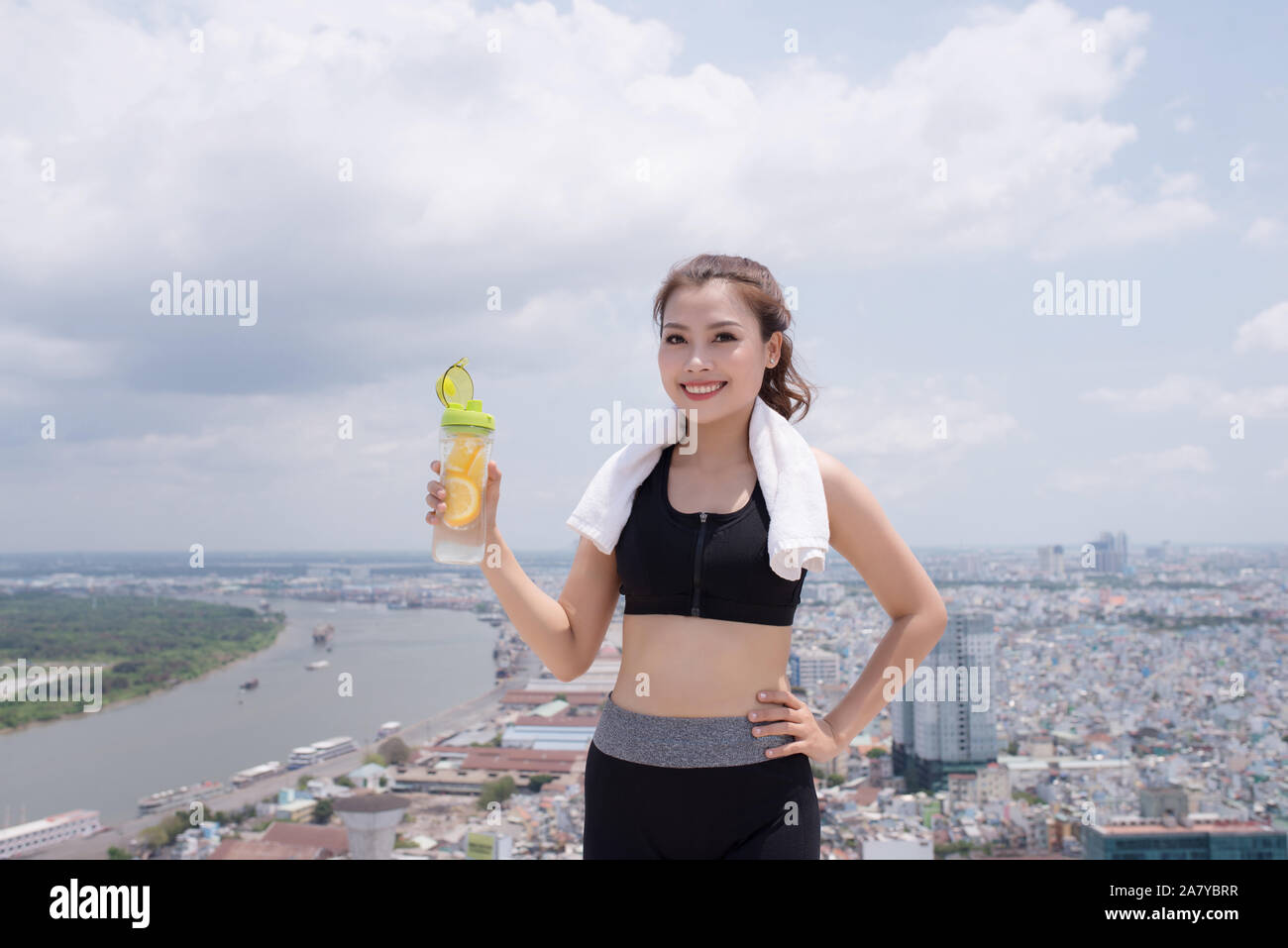 Technology and healthy lifestyle. Pretty young woman in sports wear holding bottle of water outdoors Stock Photo