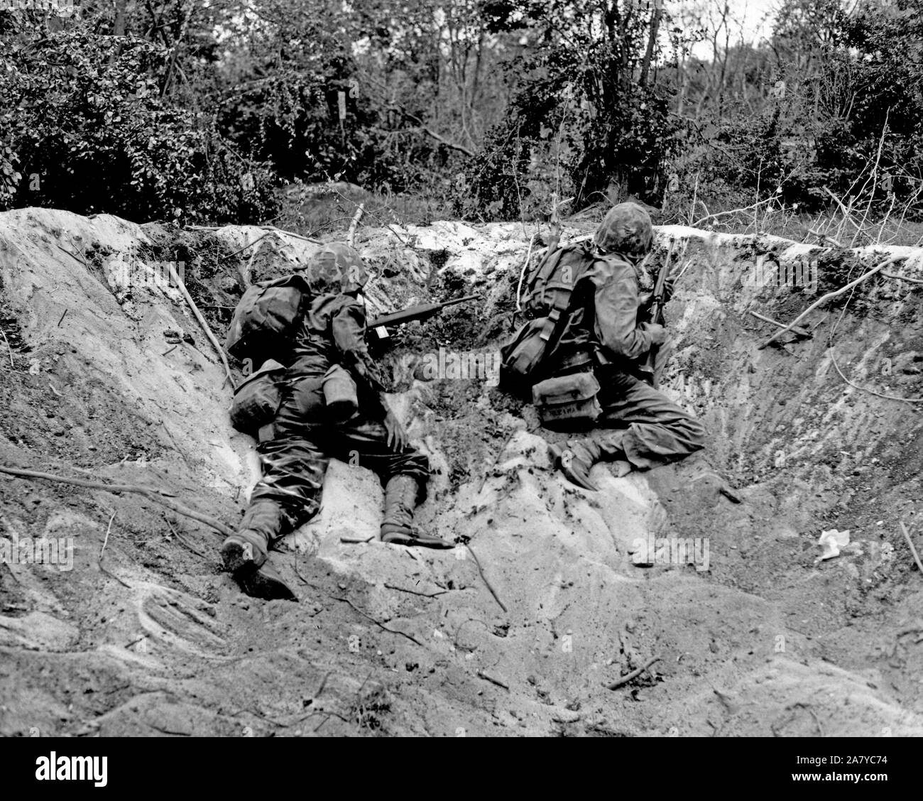 Marines crouch low in a shell hole on Saipan. Stock Photo