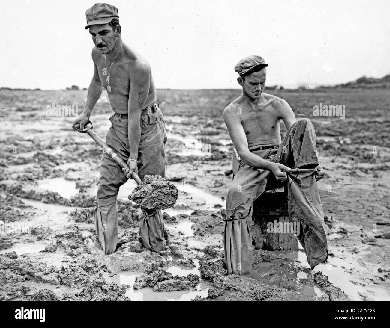 Marine tankmen shoveling mud in Okinawa, wear sandbags on their feet Stock Photo