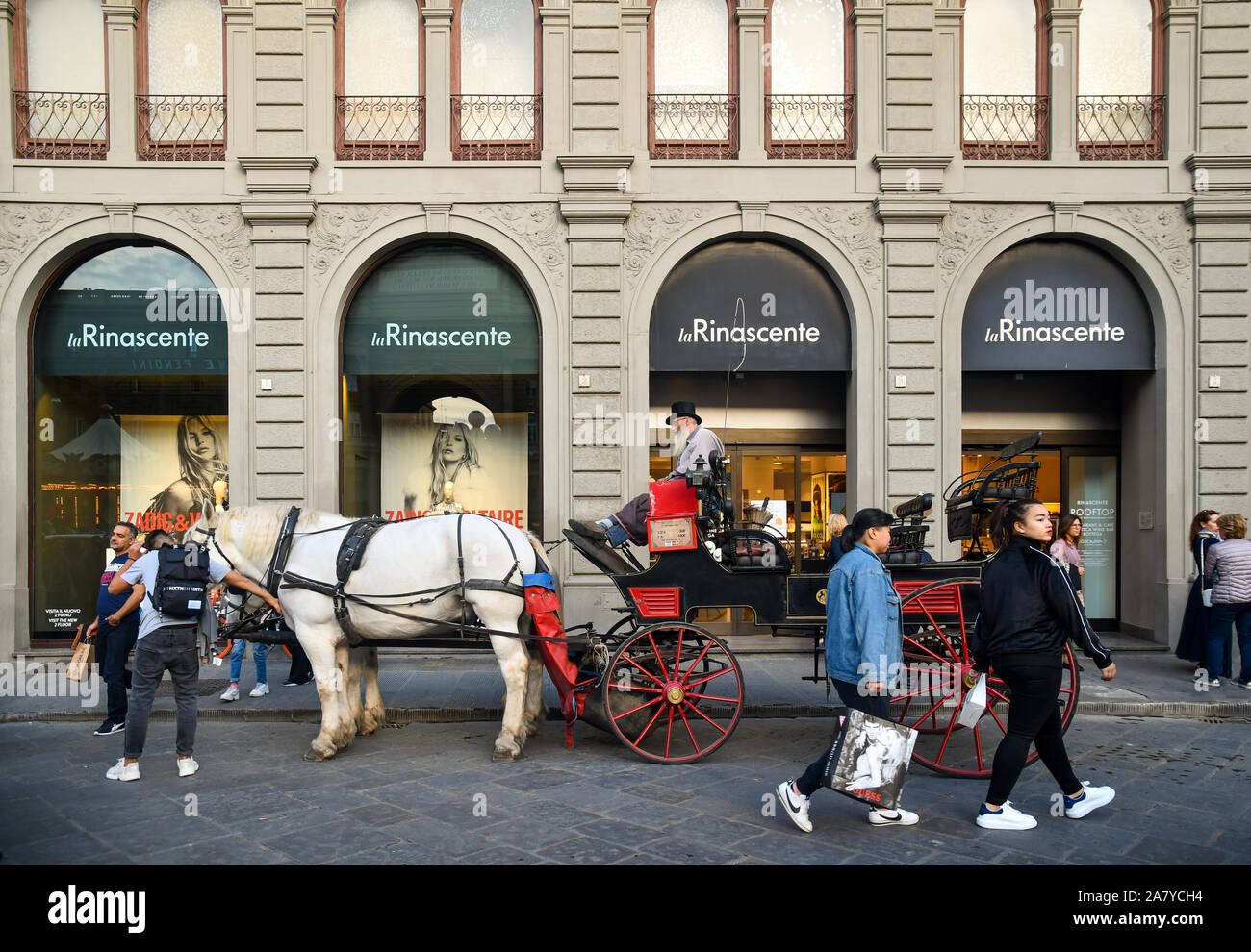 A horse-drawn carriage with coachman in front of La Rinascente department store with tourists in the city center of Florence, Tuscany, Italy Stock Photo