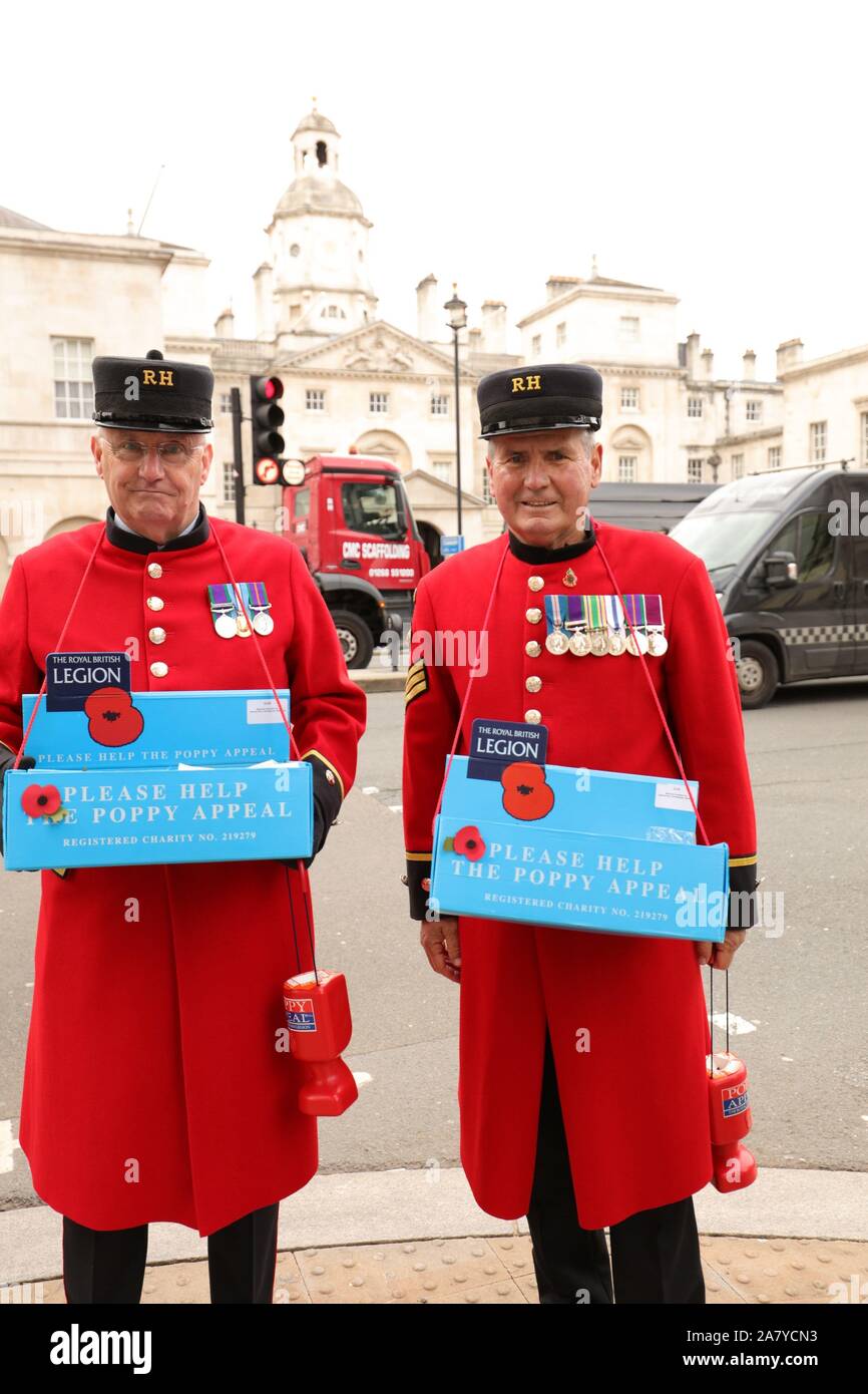 Chelsea Pensioners in red uniforms seen helping  the Poppy Appeal for remembrance of those lost serving the armed forces, on Whitehall, London UK Stock Photo