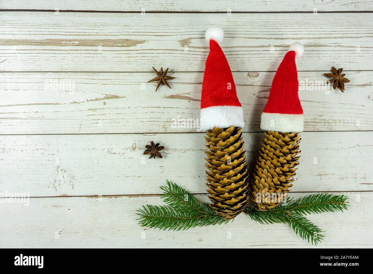 two santa hats on pine cones layout on white wooden background symbol of togetherness at christmas . Stock Photo