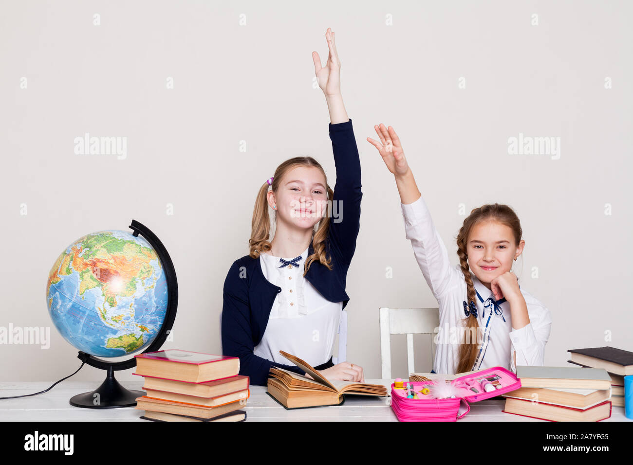 two schoolgirl girls with books and a globe in class at the desk Stock ...