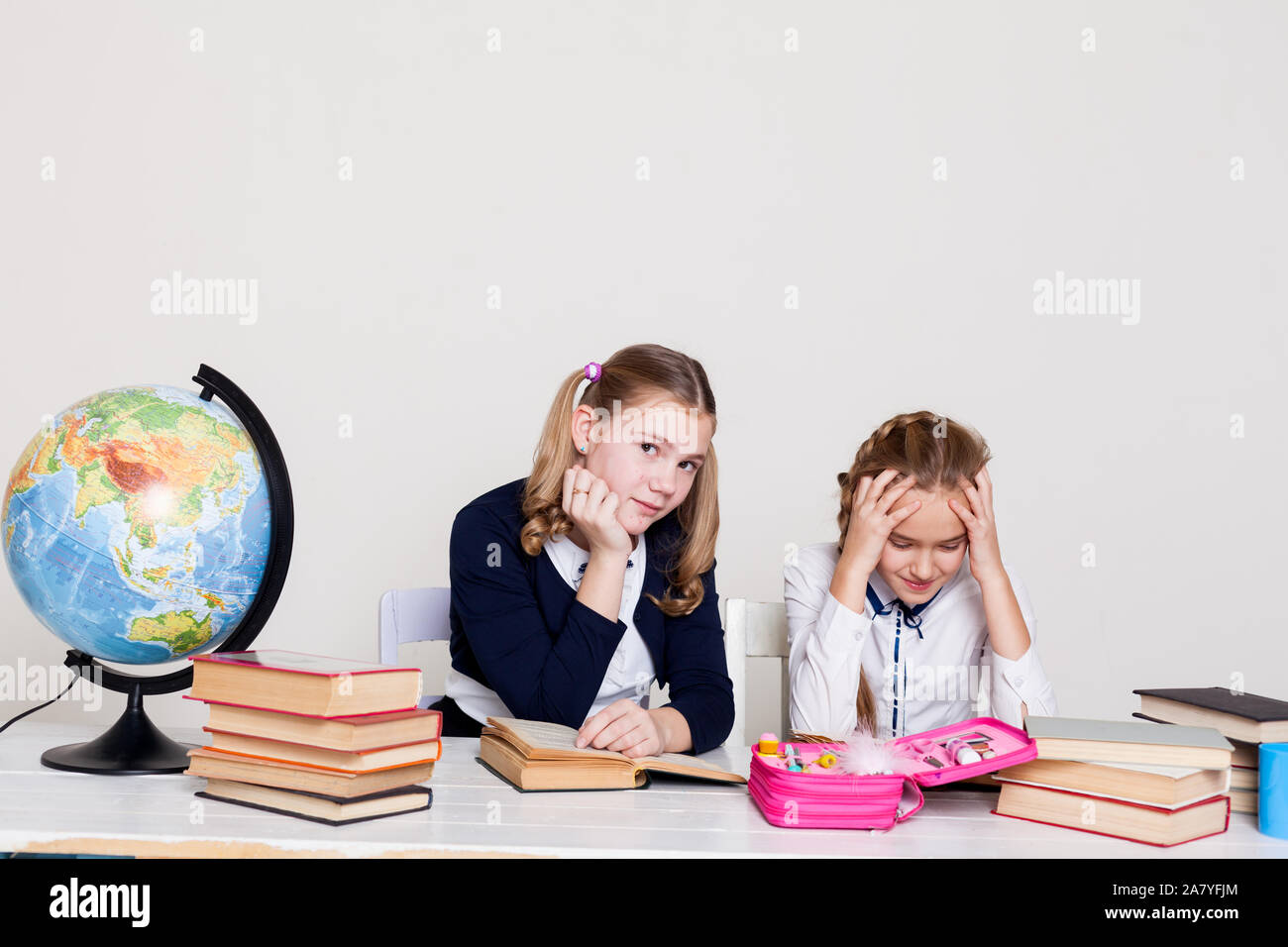 two schoolgirl girls with books and a globe in class at the desk Stock ...