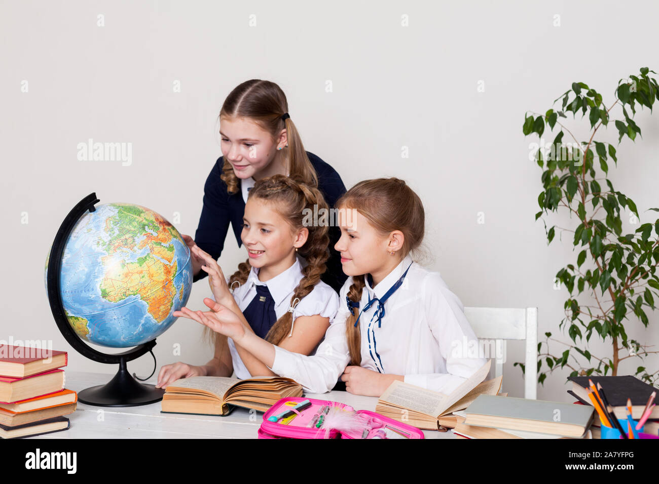 three girls with books and a globe in geography class at the desk Stock ...