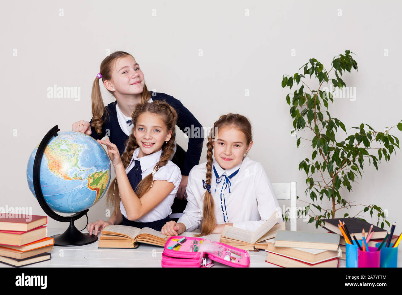 three girls with books and a globe in geography class at the desk Stock ...
