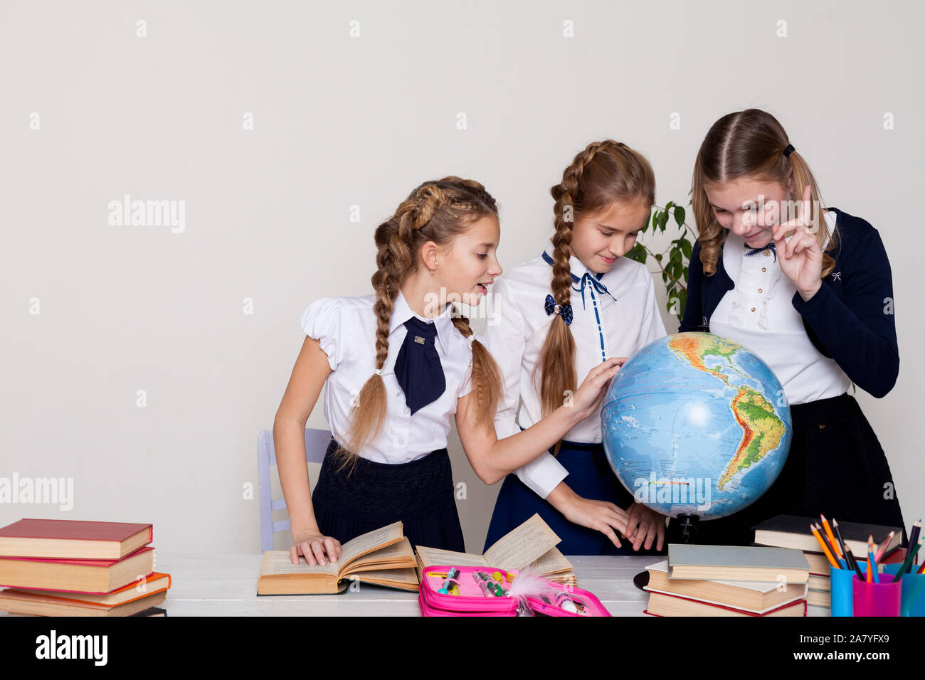 three girls with books and a globe in geography class at the desk Stock ...
