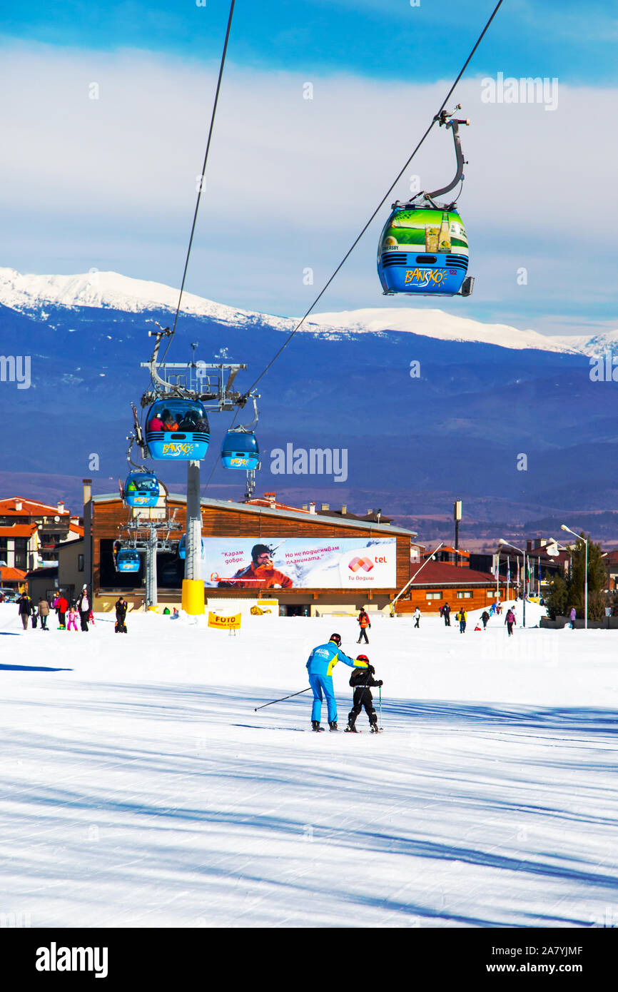 Bansko, Bulgaria - February 19, 2015: Bansko cable car cabin in Bansko, Bulgaria, people skiing. Snow mountain peaks and houses at the background Stock Photo