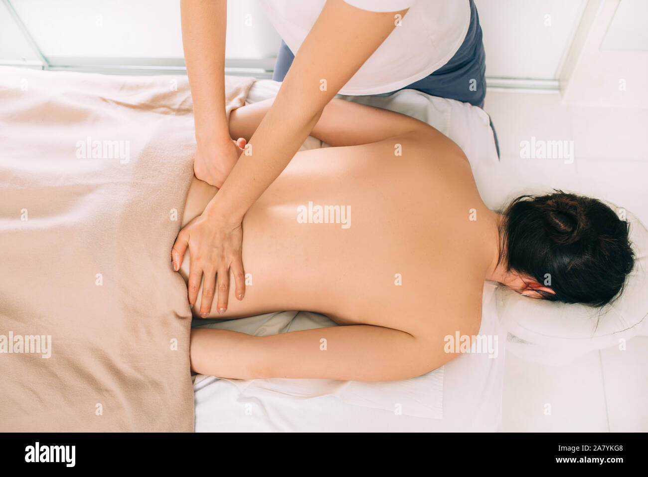 Overhead view of woman receiving back massage from therapist in