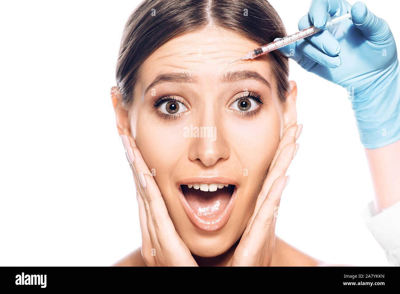 Woman with wrinkles on forehead shocked looking at camera with open mouth. Beauty injections on face, syringe near female face. Remove wrinkle and Stock Photo