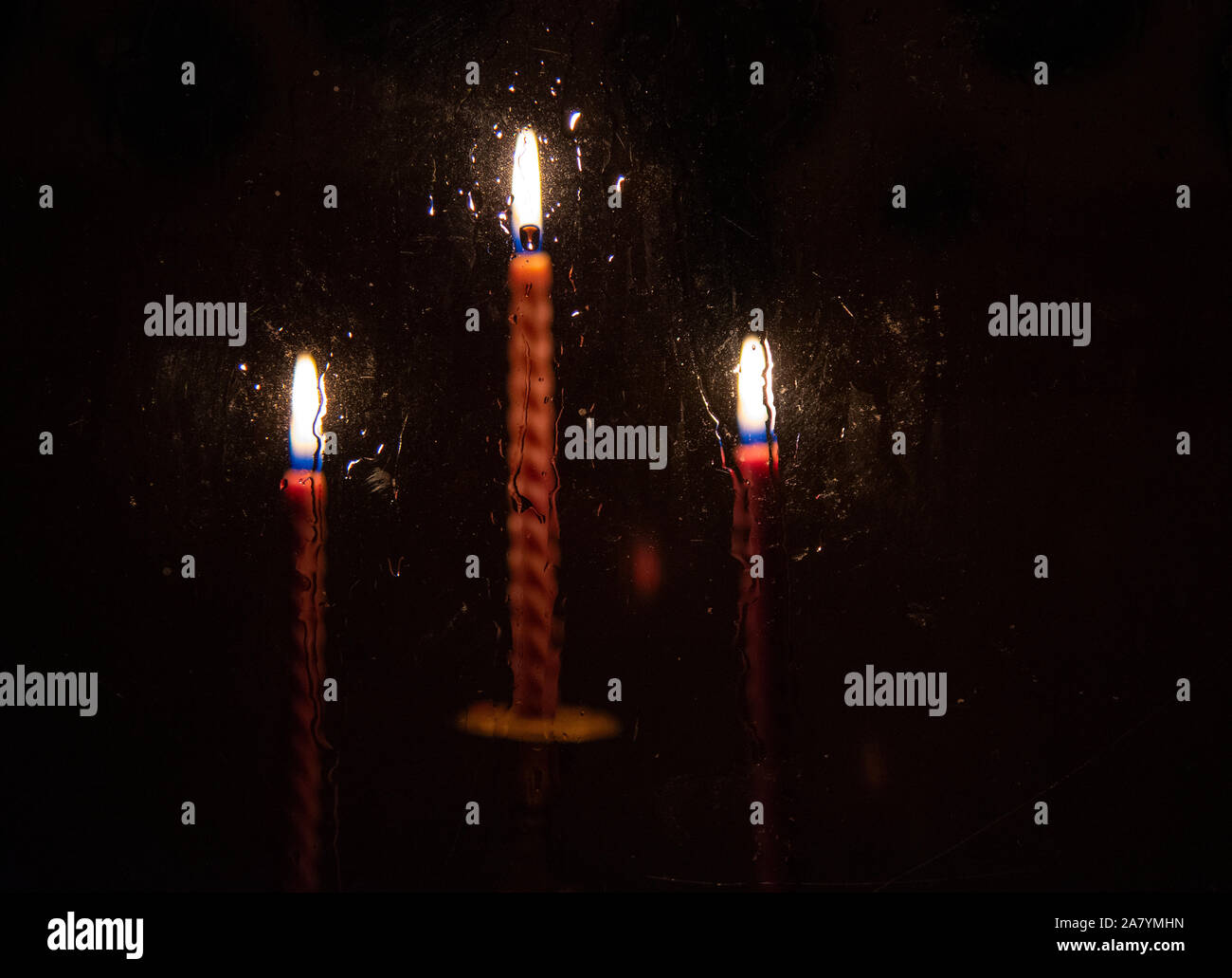 Three red candles burning in the darkness outside the window Stock