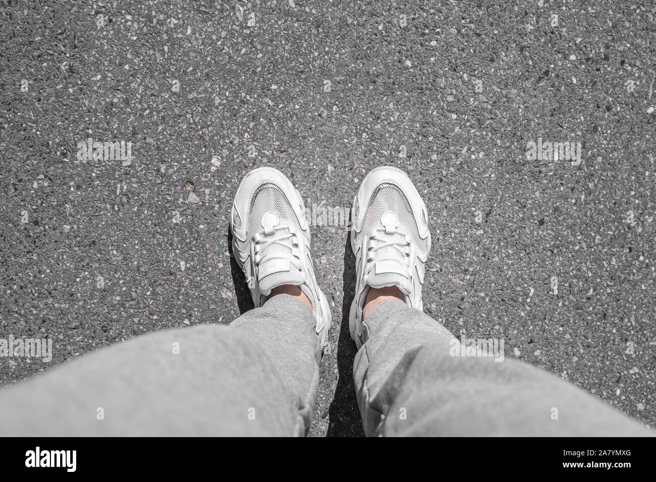 white sneakers walking on concrete. Sneakers on the pavement. Top view