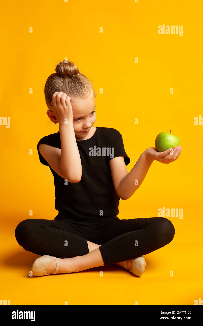 Thoughtful little dancer with apple during break Stock Photo